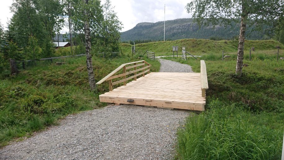 Bron över Vallgravsbäcken. I bakgrunden syns jordvallarna runt Skansen, flaggstången och berget Långåknätten.