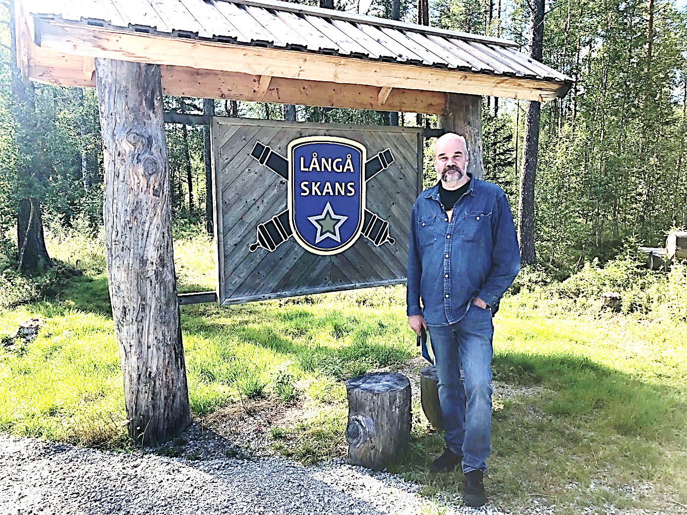 Kommunantikvarien och chefen för Härjedalens Fjällmuséum, Ola Hanneryd framför Långå Skans emblem.
